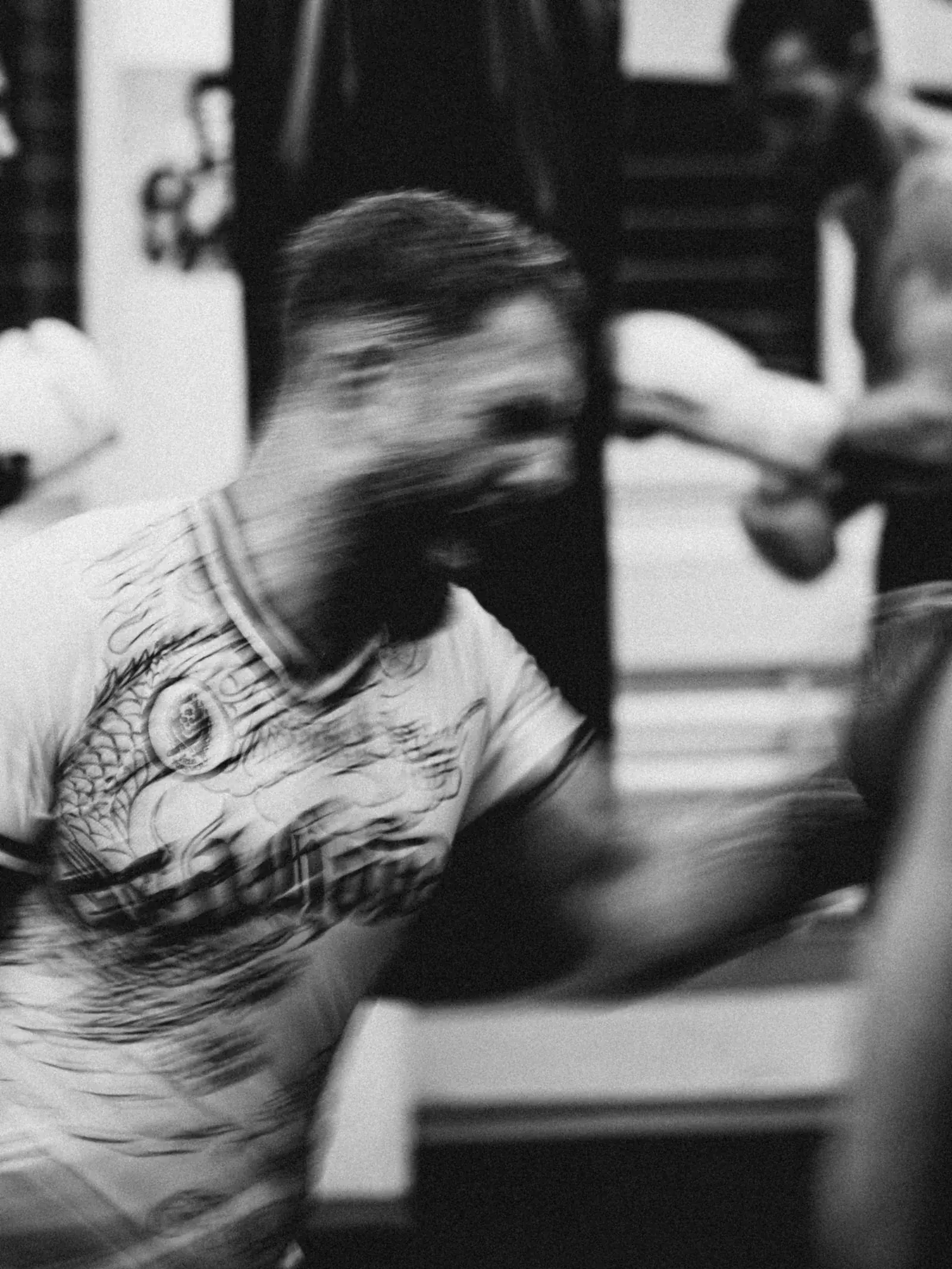 Black-and-white photo of a boxer mid-punch, moving so fast that face and arm blur.