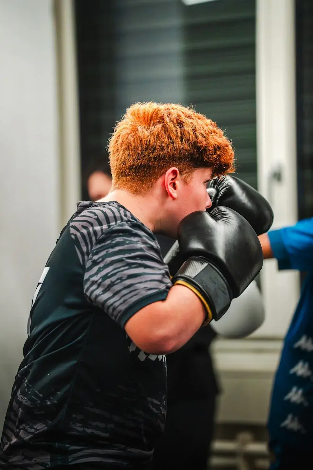 Boy in black boxing gloves holding his guard up in front of his face at Kids Boxing.