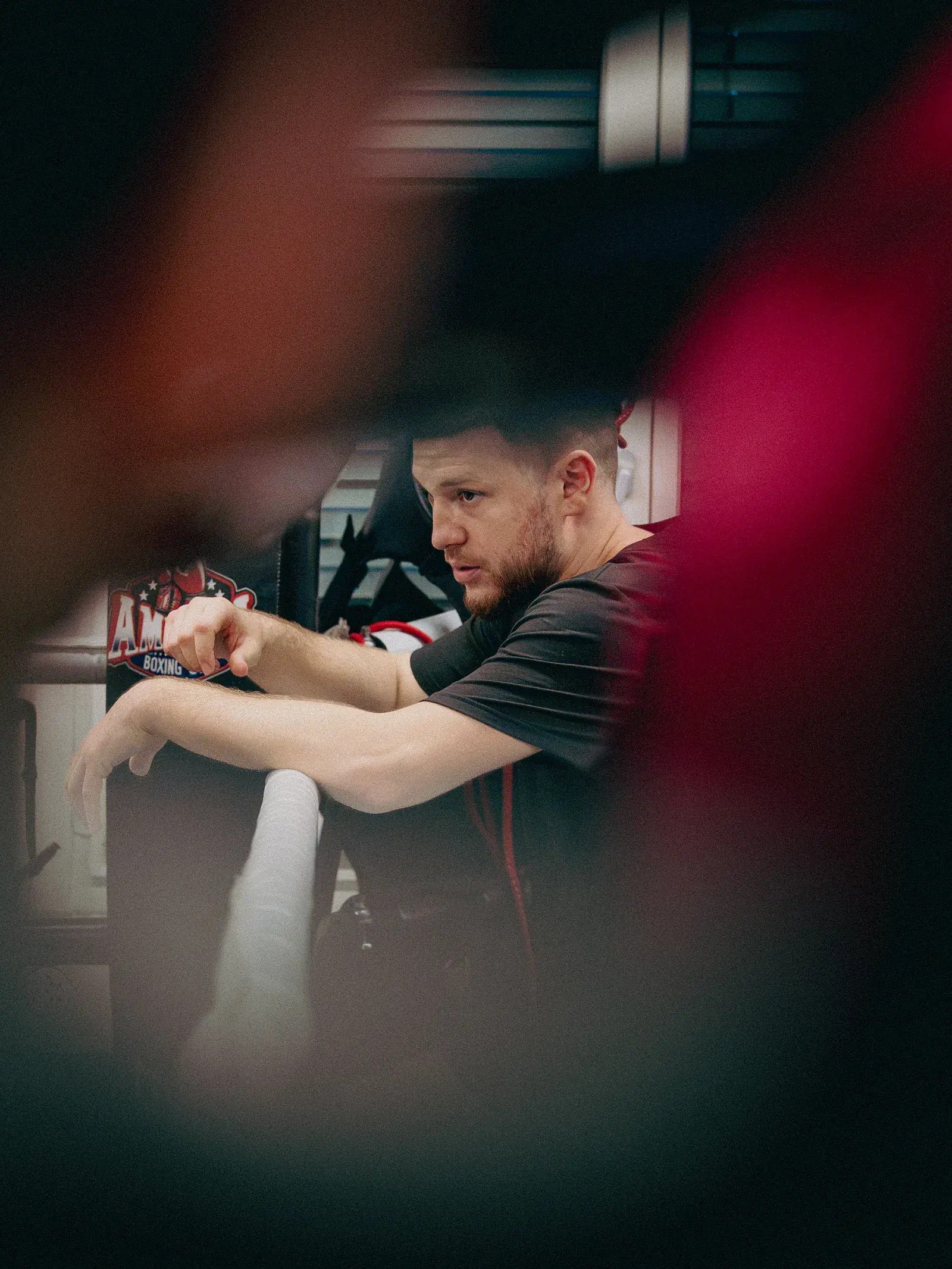 Coach leaning on the ring ropes, watching the action in the ring closely.
